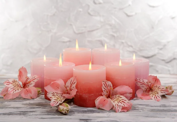 Mooie kaarsen met bloemen op tafel op grijze achtergrond — Stockfoto