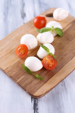 ahşap masa üstünde domates ve fesleğen ile lezzetli mozzarella peyniri