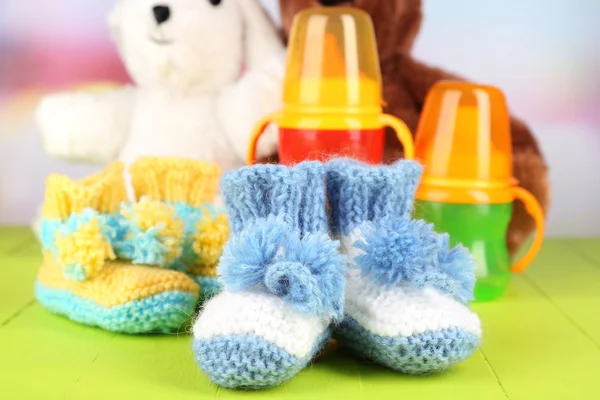 Composition with crocheted booties for baby, bottle, toy and other things on color background — Stock Photo, Image