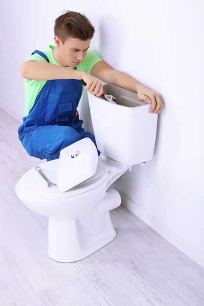 Plumber with toilet plunger on light background — Stock Photo, Image