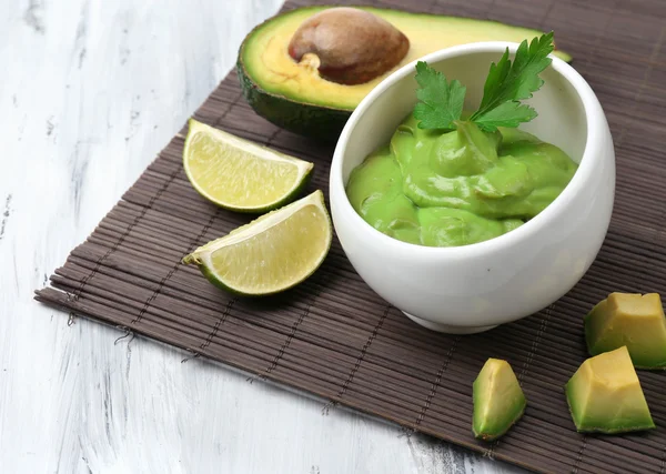 Fresh guacamole in bowl on wooden table — Stock Photo, Image