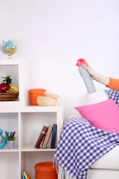 Sprayed air freshener in hand on home interior background — Stock Photo, Image