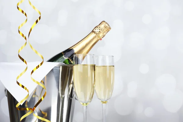 Copas de champán y botella en cubo sobre fondo claro —  Fotos de Stock