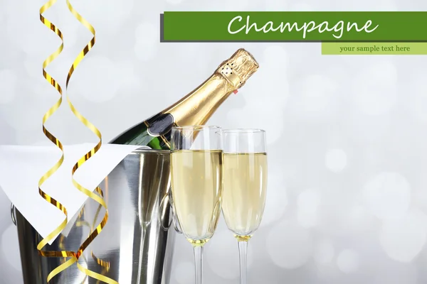 Glasses of champagne and bottle in pail on light background — Stock Photo, Image