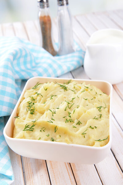 Delicious mashed potatoes with greens in bowl on table close-up