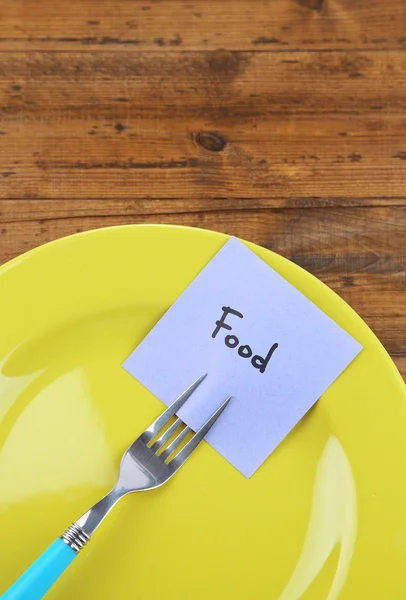 Note paper with message  attached to fork, on plate, on color wooden background — Stock Photo, Image