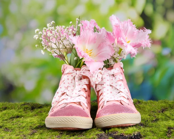 Vackra joggingskor med blommor inne på grönt gräs, på ljus bakgrund — Stockfoto