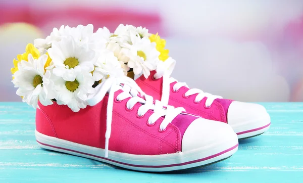 Hermosos zapatos de goma con flores en el interior en la mesa de madera, sobre fondo claro —  Fotos de Stock