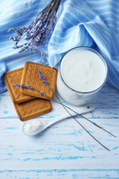 Iogurte caseiro em vidro e biscoito saboroso no fundo da mesa de madeira — Fotografia de Stock