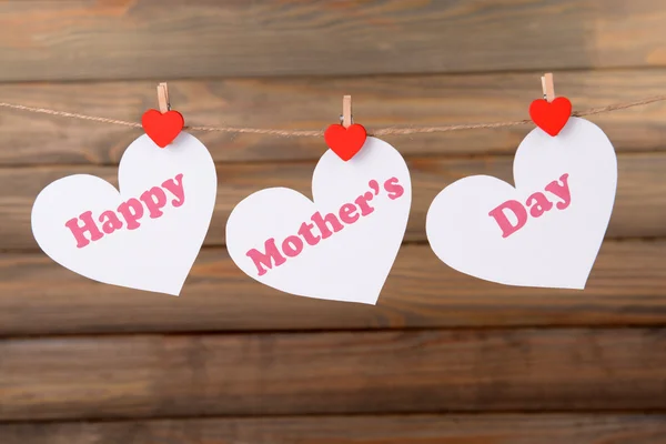 Happy Mothers Day message written on paper hearts on brown background — Stock Photo, Image