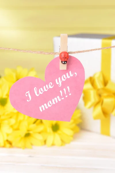 Feliz Día de las Madres mensaje escrito en papel corazón con flores sobre fondo amarillo — Foto de Stock