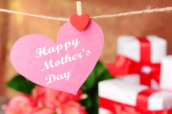 Happy Mothers Day message written on paper heart with flowers on brown background — Stock Photo, Image