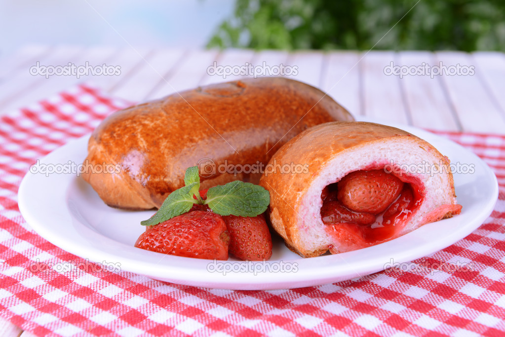 Fresh baked pasties with strawberries on plate on table close-up