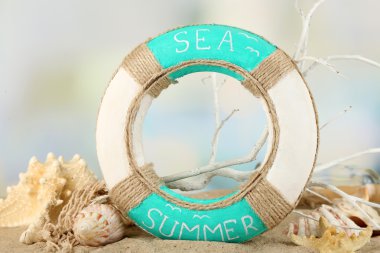 Lifebuoy ve deniz kabukları üzerinde açık renkli kum üzerinde