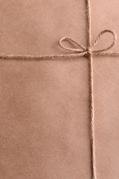 Нитка, завязанная бантом на бумажной упаковке крупным планом — стоковое фото