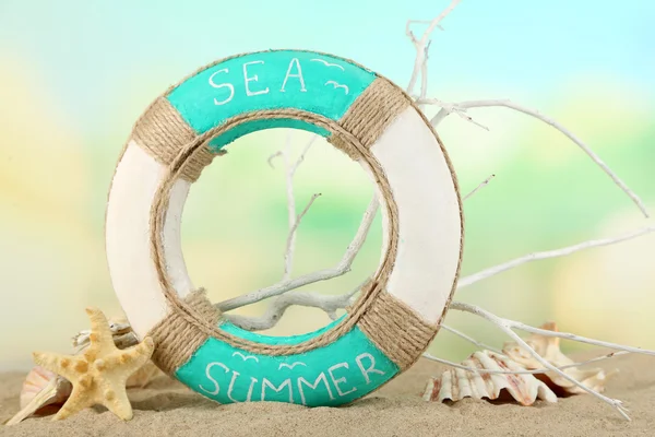 在明亮的背景上的沙子，救生圈和海贝壳 — 图库照片