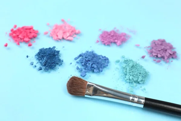 Rainbow crushed eyeshadow and professional make-up brush on blue background — Stock Photo, Image