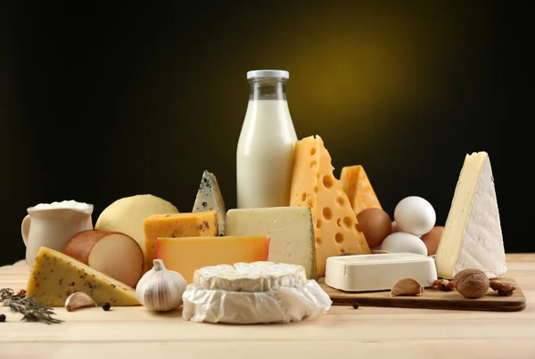 Productos lácteos sabrosos sobre mesa de madera, sobre fondo oscuro — Foto de Stock