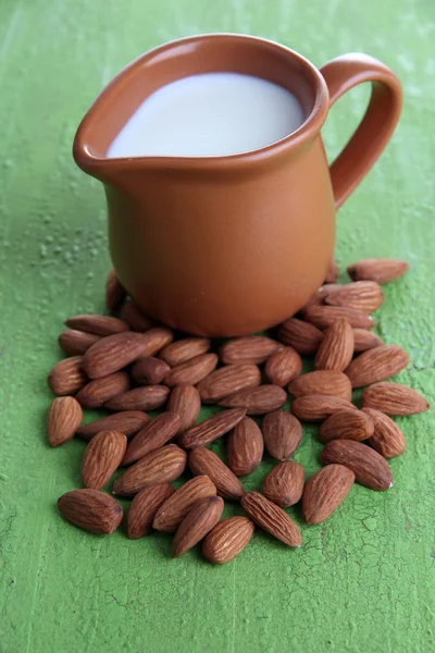 Susu almond dalam kendi dengan almond dalam mangkuk, pada warna latar belakang kayu — Stok Foto
