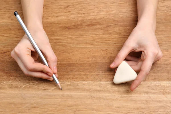 Mänskliga händer med penna och radera gummi på träbord bakgrund — Stockfoto