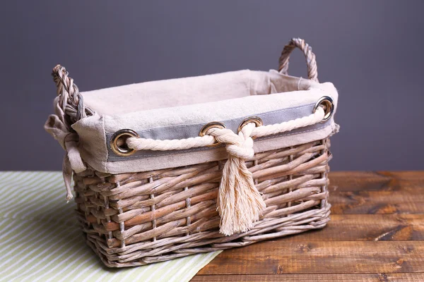 Cesta de vime vazia na mesa de madeira, no fundo escuro — Fotografia de Stock