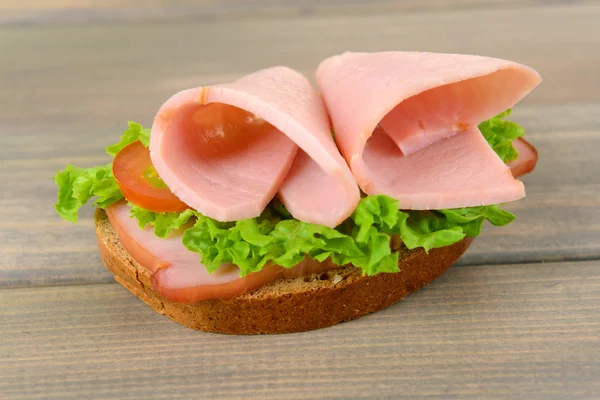 Delizioso panino con lattuga e prosciutto in tavola primo piano — Foto Stock