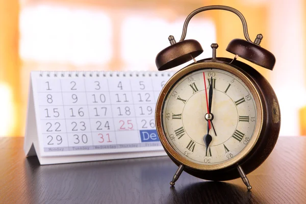 Reloj despertador y calendario sobre fondo brillante — Foto de Stock