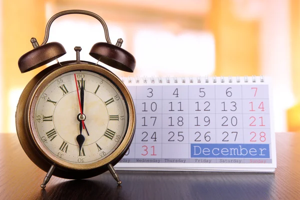 Reloj despertador y calendario sobre fondo brillante — Foto de Stock