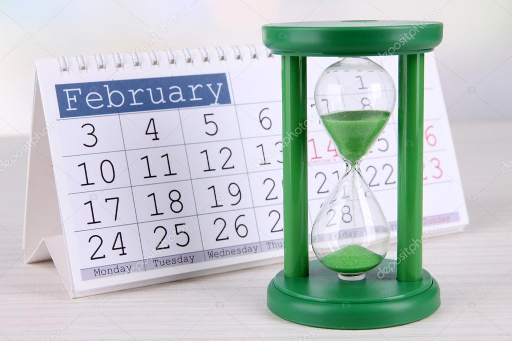 Hourglass and calendar on bright background