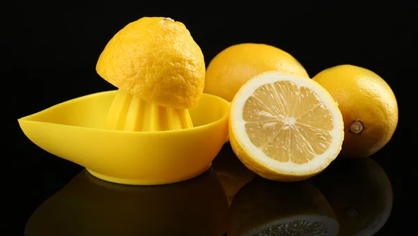 Citrus squeezer with lemons on black background — Stock Photo, Image