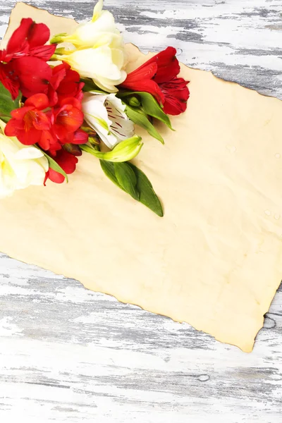 Beautiful Alstroemeria flowers and empty sheet on wooden table — Stock Photo, Image
