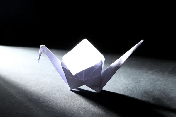 Origami crane on dark background with light — Stock Photo, Image