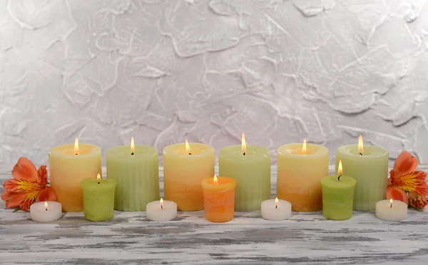 Mooie kaarsen met bloemen op tafel op grijze achtergrond — Stockfoto