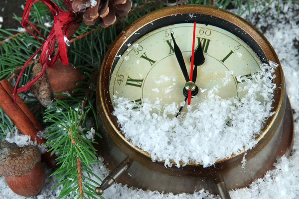 Reloj con ramas de abeto y decoraciones de Navidad bajo la nieve de cerca — Foto de Stock