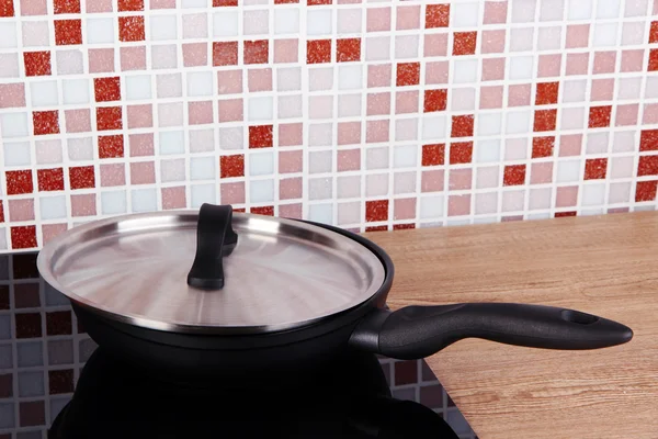 Pot on stove in kitchen on table on mosaic tiles background — Stock Photo, Image