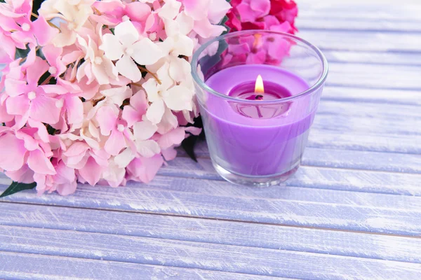 Belas velas coloridas e flor, na cor de fundo de madeira — Fotografia de Stock