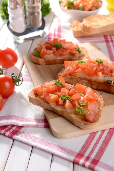 Deliciosa bruschetta con tomates en la tabla de cortar de cerca —  Fotos de Stock