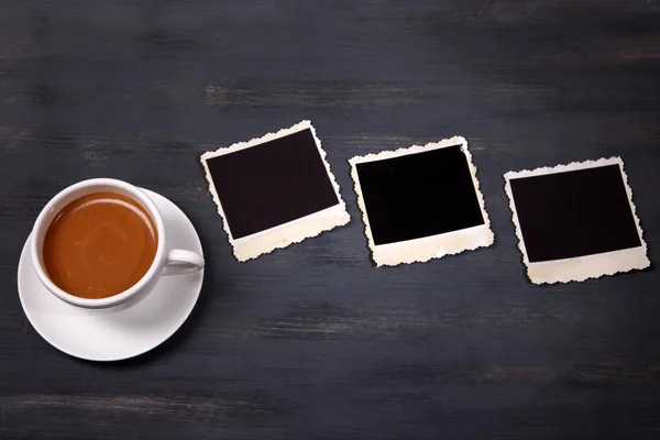 Koffiekopje en oude foto's in het lege, op houten achtergrond — Stockfoto