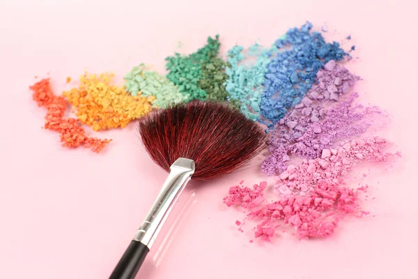 Rainbow crushed eyeshadow and professional make-up brush on pink background — Stock Photo, Image