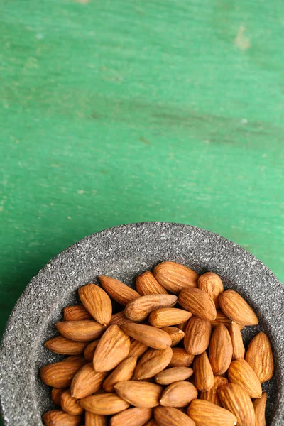 Almendras en tazón sobre fondo de madera de color — Foto de Stock