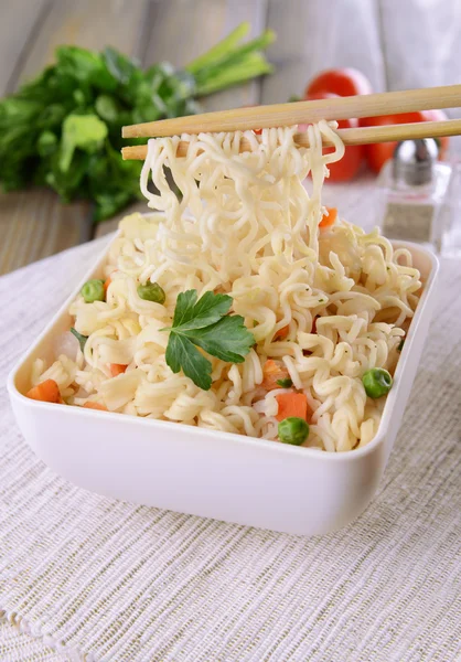 Tasty instant noodles with vegetables in bowl on table close-up — Stock Photo, Image