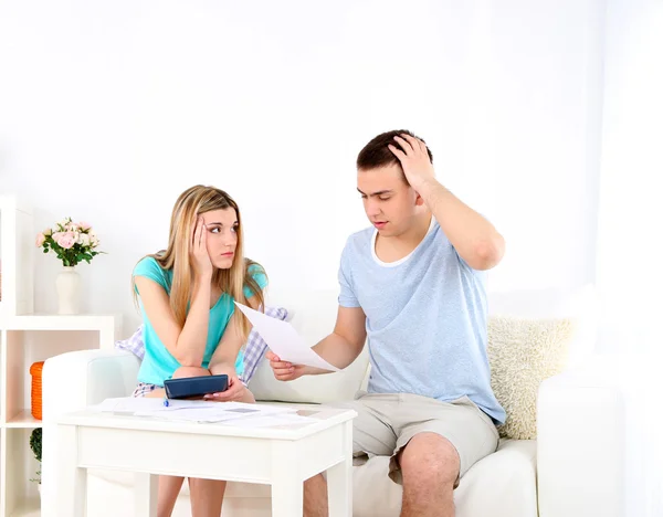 Casal jovem calculando finanças na mesa, em casa fundo interior — Fotografia de Stock