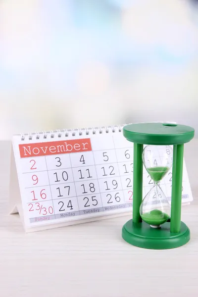 Přesýpací hodiny a kalendář na světlé pozadí — Stock fotografie