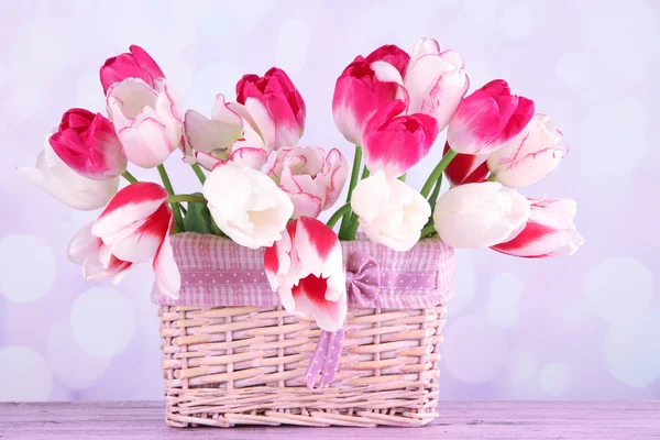 Beautiful tulips in wicker basket, on light background — Stock Photo, Image