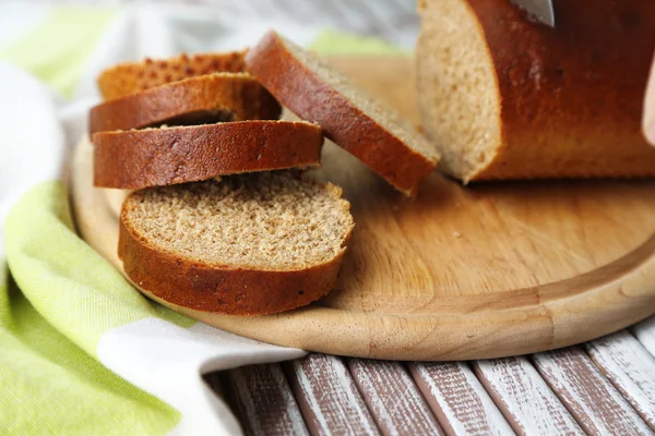 Dámské ruce krájení chleba na dřevěné desce, detailní záběr — Stock fotografie