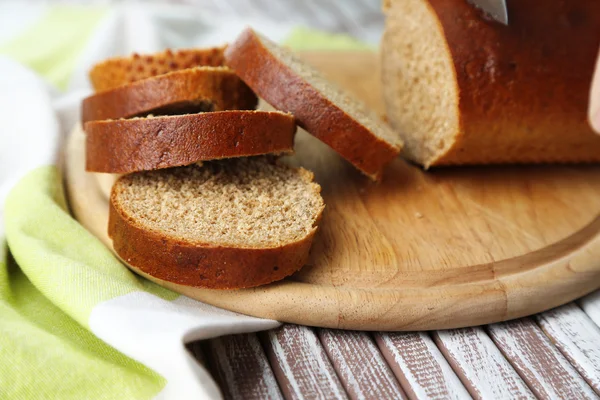 Mani femminili taglio del pane su tavola di legno, primo piano — Foto Stock