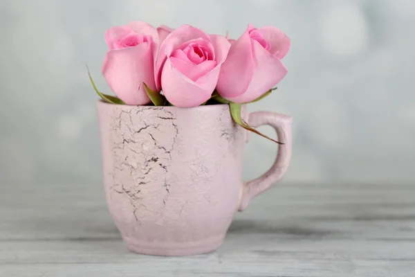 Beautiful roses in cup on light background — Stock Photo, Image