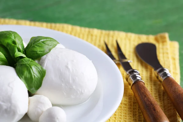 Sabroso queso mozzarella con albahaca en plato sobre fondo de madera — Foto de Stock