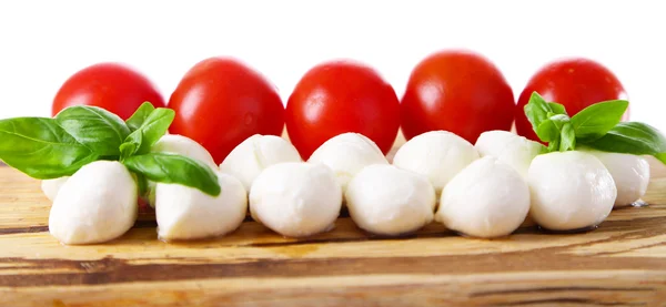 Smakelijke mozzarella kaas ballen met basilicum en rode tomaten, op snijplank, geïsoleerd op wit — Stockfoto
