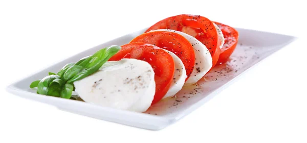 モッツァレラチーズ、トマト、白で隔離され、プレート上のバジルのカプレーゼ サラダ — ストック写真